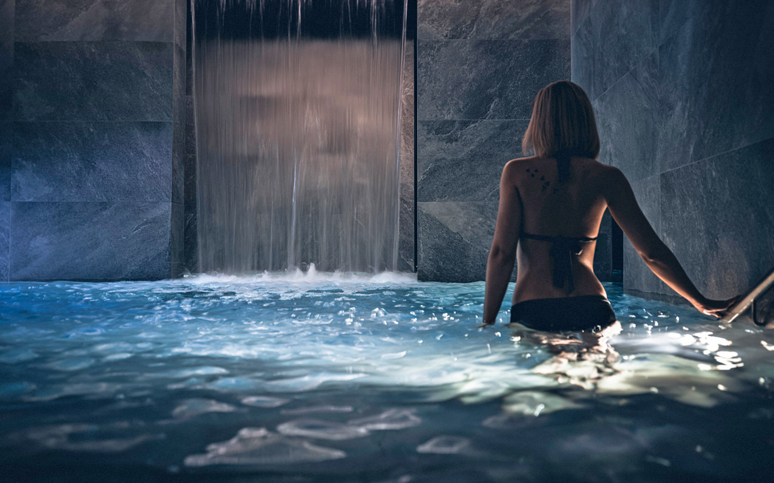 jeune femme se baignant dans une piscine avec cascade